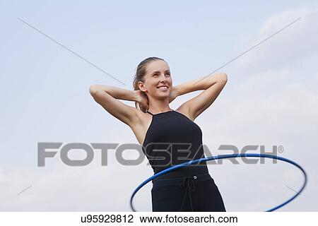 Stock Image - Russia, Voronezh, young woman exercising with hula hoop. Fotosearch