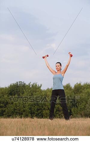 Stock Photo - Russia, Voronezh, young woman exercising in field. Fotosearch
