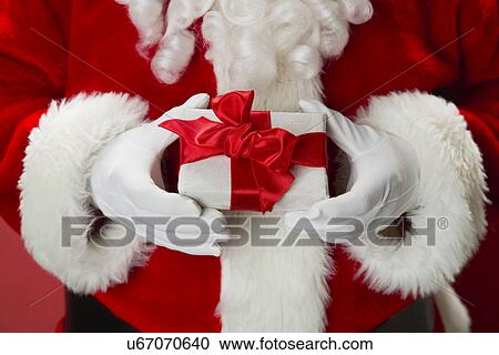 Stock Image - Santa Claus holding gift. Fotosearch