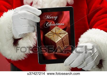 Picture - Santa Claus holding tablet with image of gift. Fotosearch