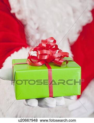 Santa clause holding Christmas gift View Large Photo Image Stock Photo - Santa clause holding Christmas gift. Fotosearch