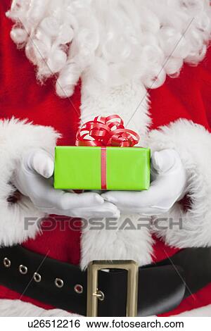 Stock Photograph - Santa clause holding Christmas gift. Fotosearch