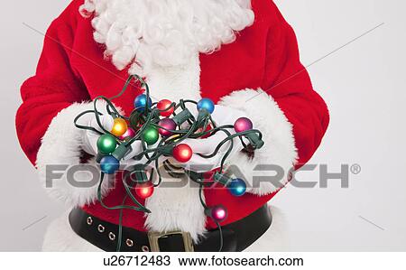 Stock Image - Santa clause holding fairy lights. Fotosearch