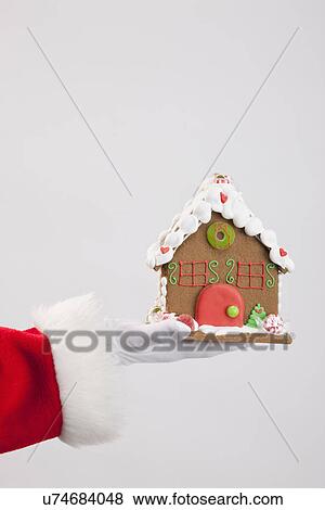Stock Photo - Santa clause holding gingerbread house. Fotosearch