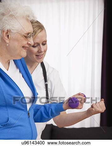 Stock Image - Senior woman exercising with nurse. Fotosearch
