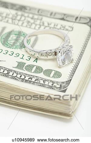 Silver ring on bunch of dollar banknotes, studio shot View Large Photo Image Stock Photo - Silver ring on bunch of dollar banknotes, studio shot. Fotosearch