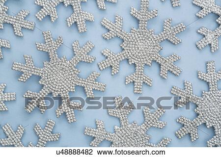 Stock Image - Silver snowflakes on blue background. Fotosearch