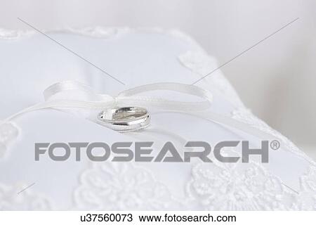 Stock Image - Silver wedding ring on white cushion. Fotosearch