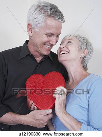 Smiling mature couple with heart shaped box View Large Photo Image Stock Image - Smiling mature couple with heart shaped box. Fotosearch
