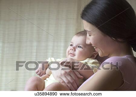 Smiling mother holding baby (6-11 months) View Large Photo Image Stock Image - Smiling mother holding baby (6-11 months). Fotosearch