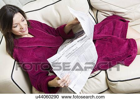 Smiling woman reading newspaper on sofa View Large Photo Image Stock Image - Smiling woman reading newspaper on sofa. Fotosearch