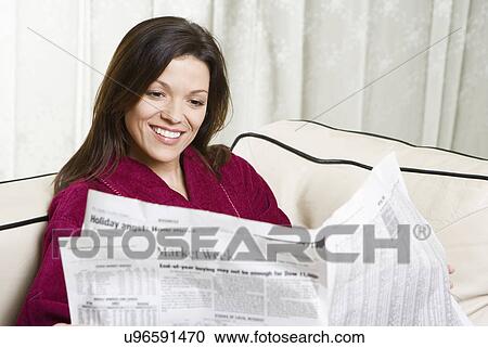 Smiling woman reading newspaper on sofa View Large Photo Image Stock Image - Smiling woman reading newspaper on sofa. Fotosearch