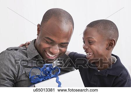Son (6-7) giving present to his father, studio shot View Large Photo Image Stock Image - Son (6-7) giving present to his father, studio shot. Fotosearch