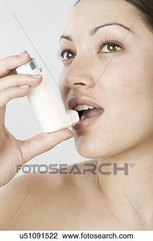 Stock Image - South Africa, Cape Town, close-up of young woman using asthma inhaler. Fotosearch
