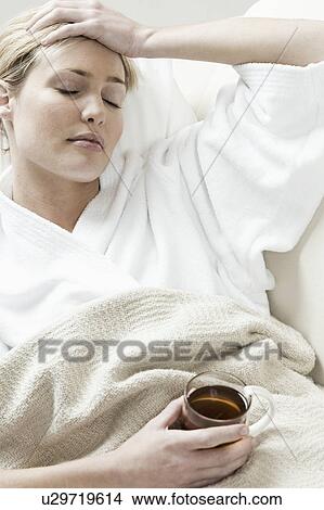 Picture - South Africa, Cape Town, Sick young woman lying in bed with tea. Fotosearch