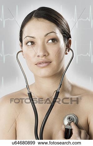 Stock Photo - South Africa, Cape Town, Young woman examining self with stethoscope, pulse trace in background. Fotosearch