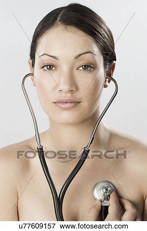 Stock Photo - South Africa, Cape Town, Young woman examining self with stethoscope. Fotosearch