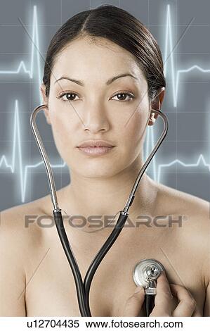 Stock Photography - South Africa, Cape Town, Young woman examining self with stethoscope, pulse trace in background. Fotosearch