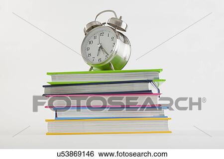 Stock Photograph - Stack of colorful books with alarm clock on top. Fotosearch