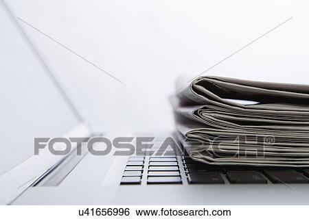 Stock Photograph - Stack of newspapers on laptop. close-up. Fotosearch