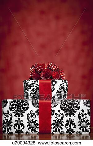 Stock Photo - Stack of presents wrapped in wrapping paper with damask pattern on red background, studio shot. Fotosearch