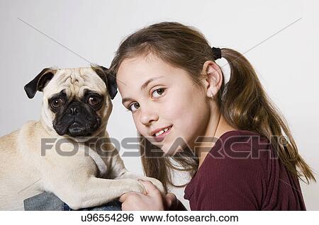 Stock Photograph - Studio portrait of smiling girl (10-11) with pug. Fotosearch