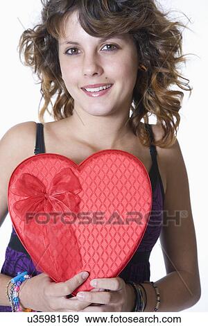 Studio portrait of smiling teenage girl (14-15) with heart shaped box View Large Photo Image Stock Photo - Studio portrait of smiling teenage girl (14-15) with heart shaped box. Fotosearch