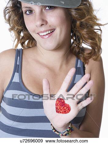 Stock Photo - Studio portrait of smiling teenage girl (14-15) with heart drawn on hand. Fotosearch