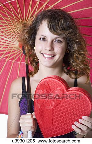 Studio portrait of smiling teenage girl (14-15) with heart shaped box and umbrella View Large Photo Image Stock Photography - Studio portrait of smiling teenage girl (14-15) with heart shaped box and umbrella. Fotosearch