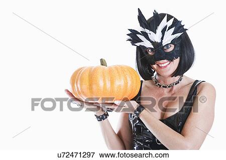Studio portrait of woman wearing mask and holding pumpkin View Large Photo Image Stock Photo - Studio portrait of woman wearing mask and holding pumpkin. Fotosearch