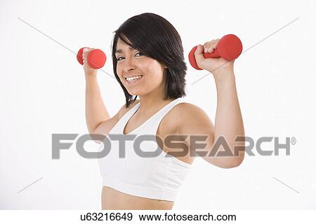 Stock Photo - Studio portrait of young woman lifting dumbbells. Fotosearch