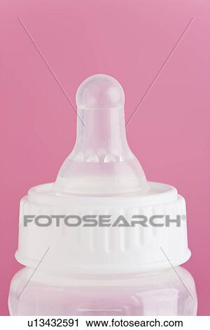 Stock Image - Studio shot of baby bottle on pink background. Fotosearch