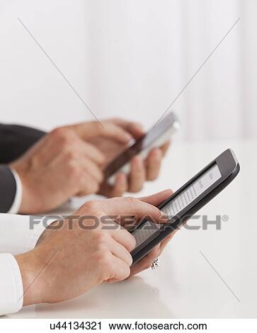 Studio shot of business people using e-books, close-up View Large Photo Image Stock Image - Studio shot of business people using e-books, close-up. Fotosearch