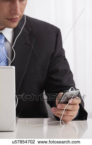 Studio shot of businessman listening to mp3 player View Large Photo Image Stock Image - Studio shot of businessman listening to mp3 player. Fotosearch