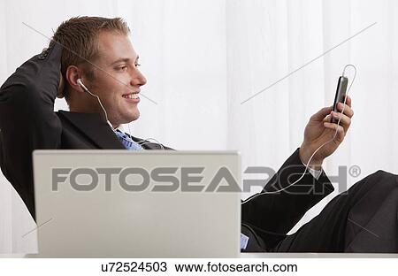 Studio shot of businessman listening to mp3 player View Large Photo Image Stock Image - Studio shot of businessman listening to mp3 player. Fotosearch