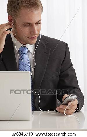 Studio shot of businessman listening to mp3 player View Large Photo Image Stock Image - Studio shot of businessman listening to mp3 player. Fotosearch
