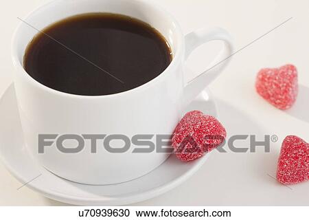 Stock Image - Studio shot of coffee cup and heart shape candies. Fotosearch
