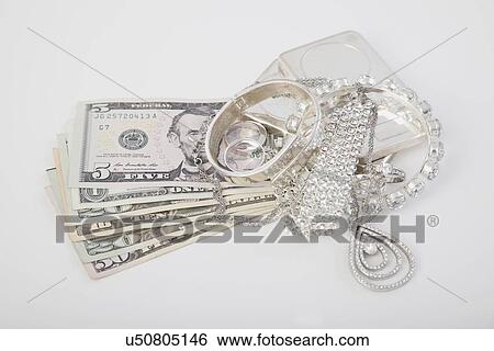 Stock Photograph - Studio shot of dollar bills and jewelry. Fotosearch