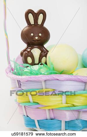 Stock Photo - Studio shot of Easter eggs and chocolate bunny in basket. Fotosearch