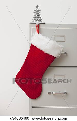 Stock Image - Studio shot of filing cabinet with small Christmas tree and Christmas stocking. Fotosearch