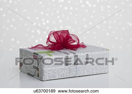 Stock Photo - Studio shot of gift wrapped in newspaper on sparkled background. Fotosearch