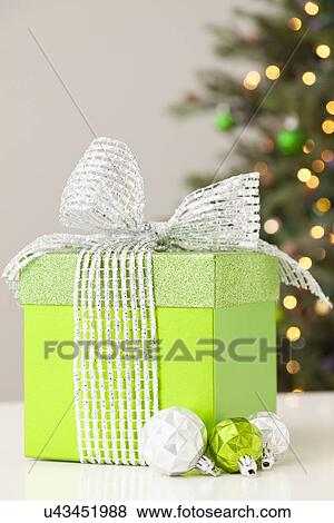 Studio shot of green gift on table with christmas tree in background View Large Photo Image Stock Photo - Studio shot of green gift on table with christmas tree in background. Fotosearch