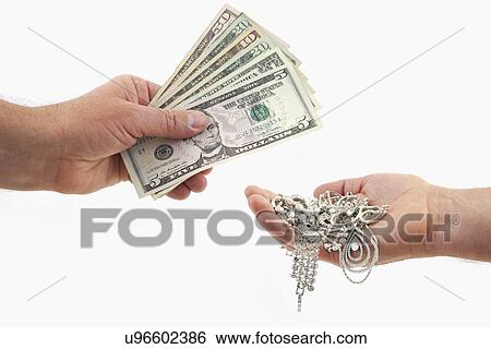 Stock Photograph - Studio shot of hands exchanging dollar bills and jewelry. Fotosearch