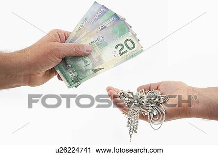 Studio shot of hands exchanging Canadian dollar bills and jewelry View Large Photo Image Stock Image - Studio shot of hands exchanging Canadian dollar bills and jewelry. Fotosearch