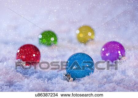 Picture - Studio shot of multicolored Christmas ornaments on artificial snow. Fotosearch