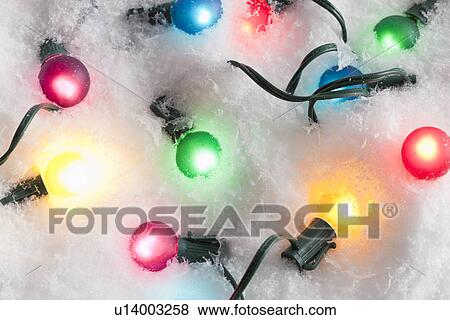 Stock Photo - Studio shot of multicolored Christmas lights on artificial snow. Fotosearch