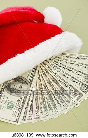 Stock Photo - Studio shot of paper currency in santa hat. Fotosearch