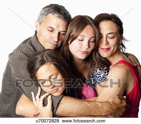 Stock Photo - Studio shot of parents and two daughters (12-13, 14-15) hugging. Fotosearch