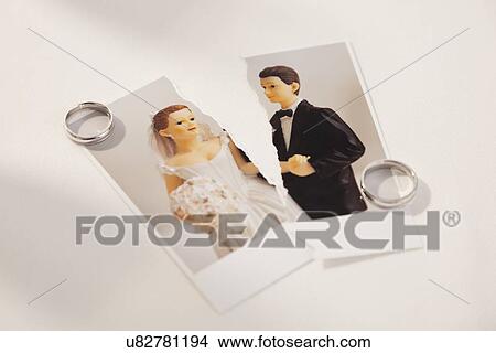 Studio shot of photo of bride and groom figurines torn in half and wedding rings View Large Photo Image Picture - Studio shot of photo of bride and groom figurines torn in half and wedding rings. Fotosearch