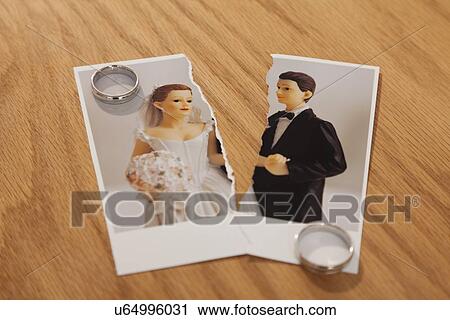 Stock Image - Studio shot of photo of bride and groom figurines torn in half and wedding rings. Fotosearch